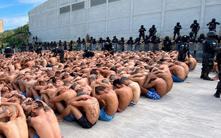 Cientos de reclusos, con las manos en la nuca, bajo custodia de agentes de seguridad durante un operativo en una cárcel de Honduras.